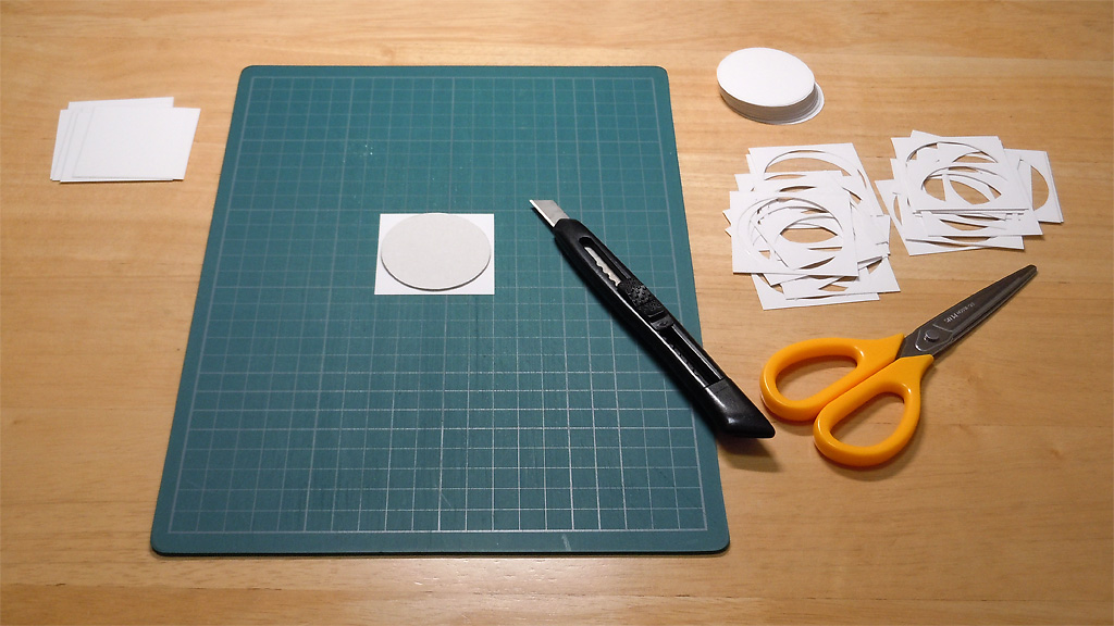 カッティングシート上にカッター、フィルム、型紙、机の隅に鋏と山積みの切断済フィルムが置かれている写真 カッティングシート上にカッター、フィルム、型紙、机の隅に鋏と山積みの切断済フィルムが置かれている写真