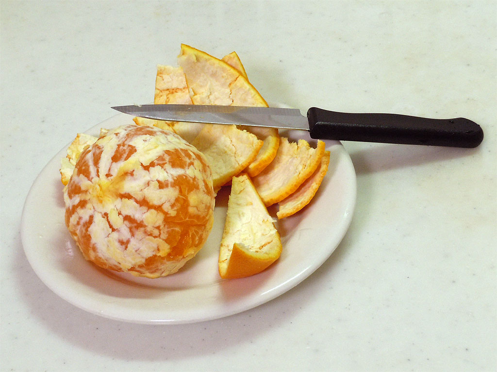 調理台、白い皿の上に皮を剥かれた清見オレンジと果物ナイフが置いてある様子